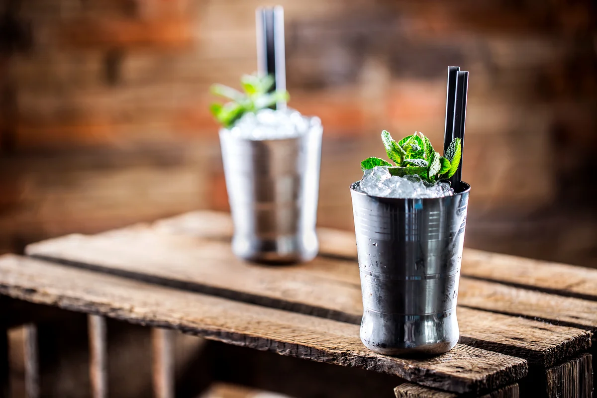 Mint julep cocktail alcoholic drink on wooden board