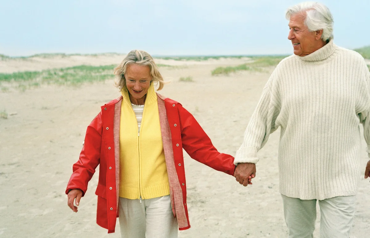 Senior couple walking hand in hand on beach
