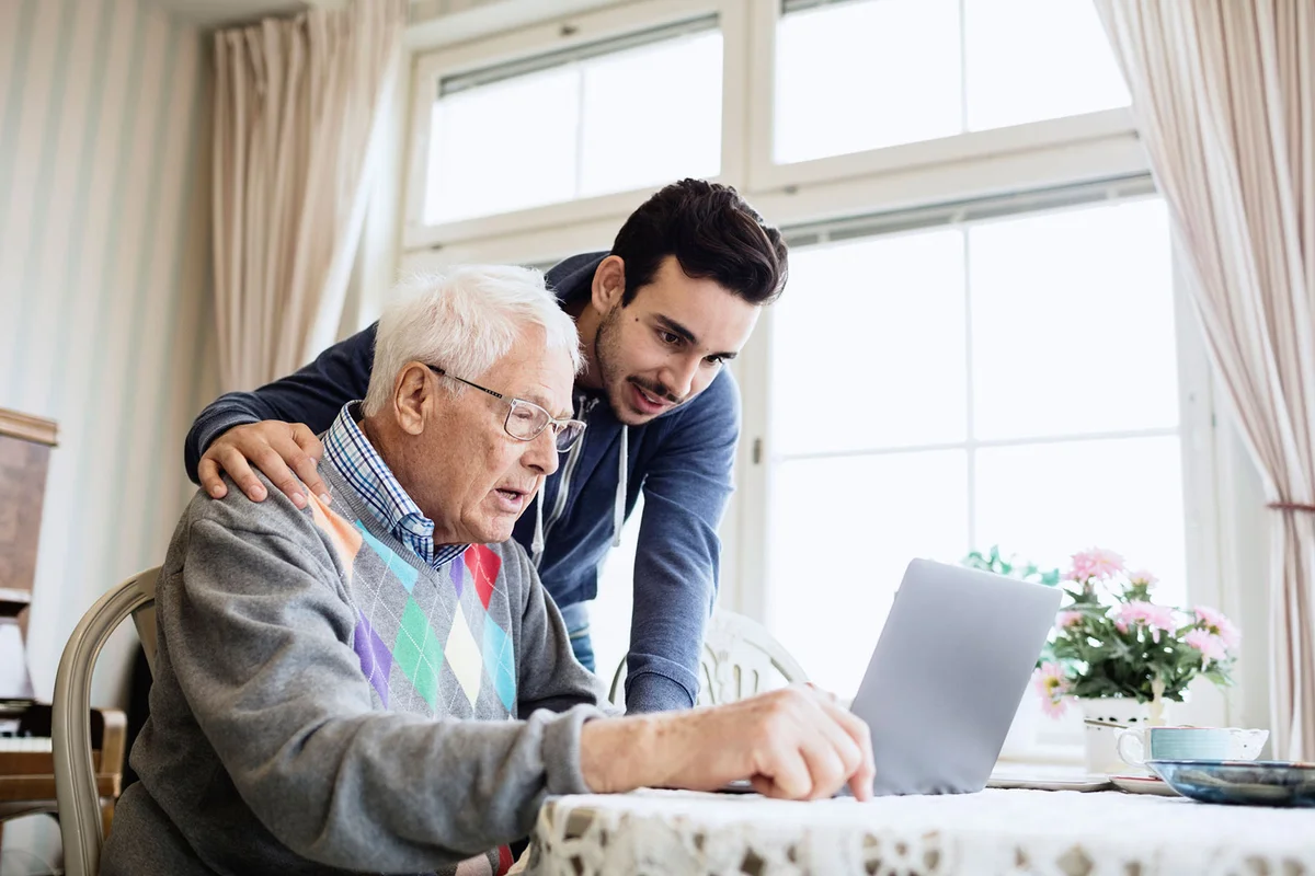 Man volunteer helping senior with computer