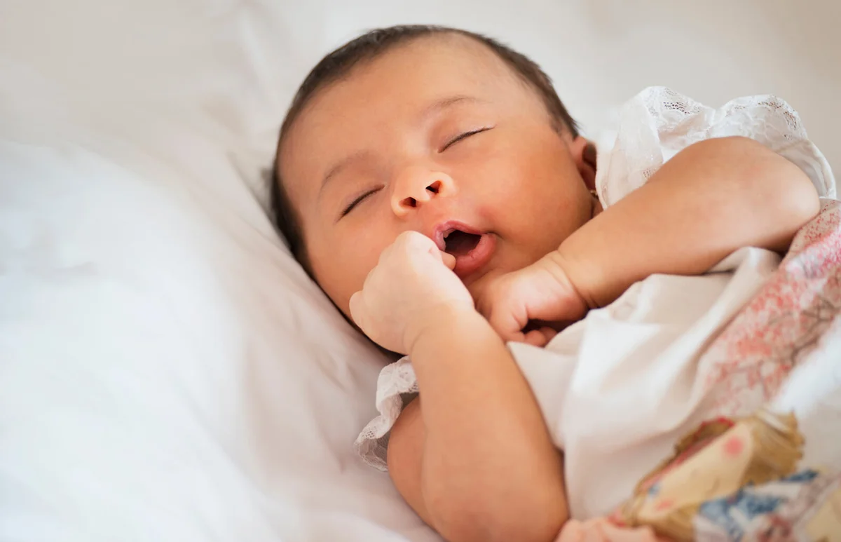 newborn baby sleeping on bed