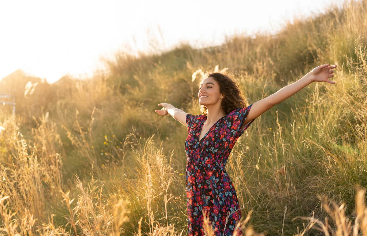 Happy young woman standing in summer meadow