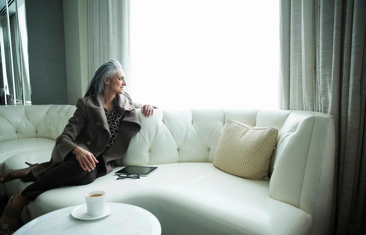Portrait of mature woman reclining on white luxury sofa