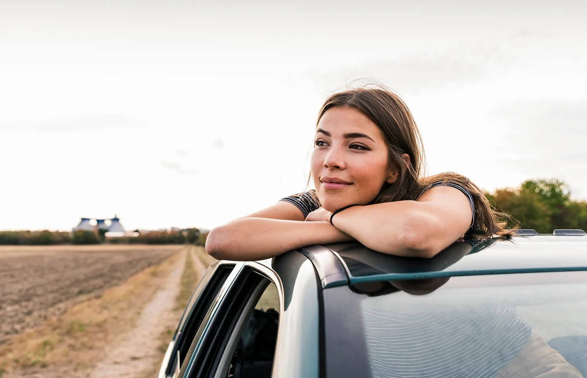 woman looking out of sunroof of a car