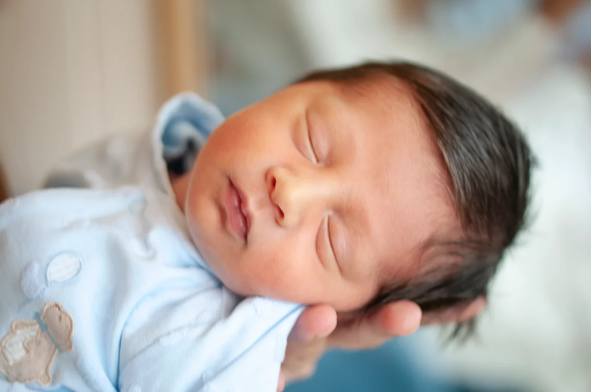 Turkish newborn sleeping in his mother's arm