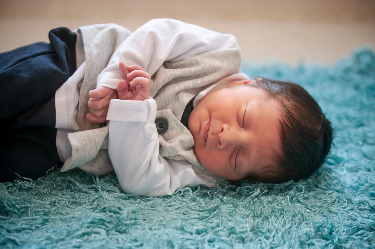 Baby boy lying on a blue rug