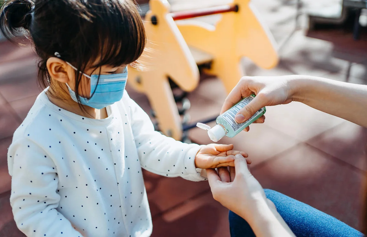 mother squeezing hand sanitizer onto little daughter's hand