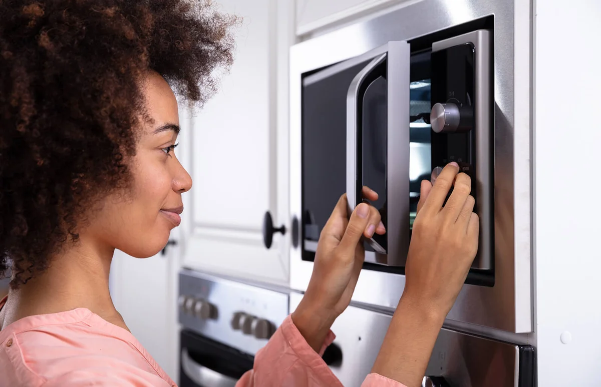 Woman Adjusting Temperature Of Microwave Oven