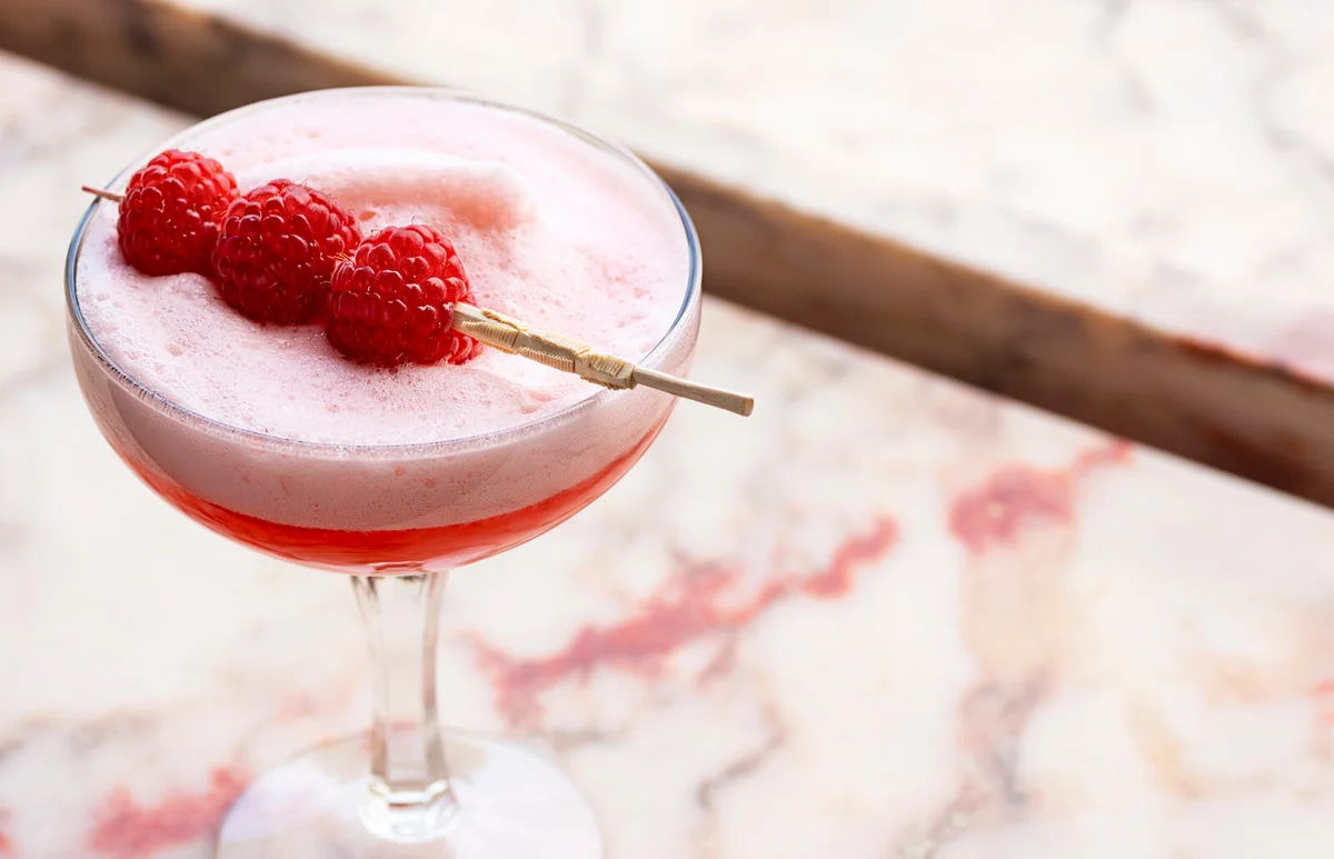 Pink Clover Club Cocktail with Egg White Foam and Raspberry Garnish
