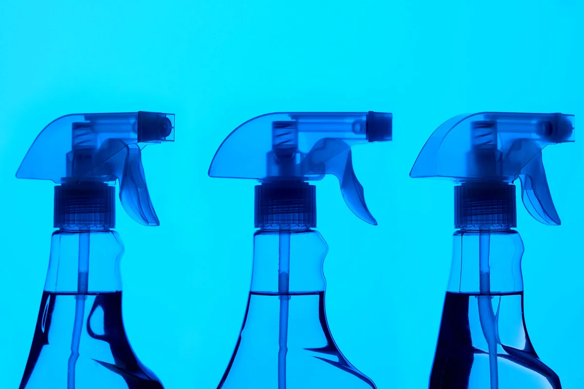 Three spray bottles on blue background