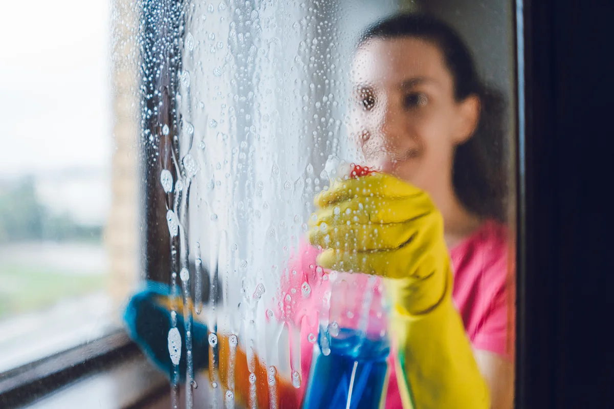 Woman spraying glass cleaner on window