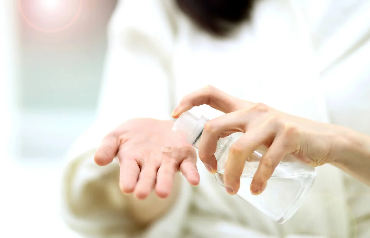 woman taking on hands liquid soap from dispenser
