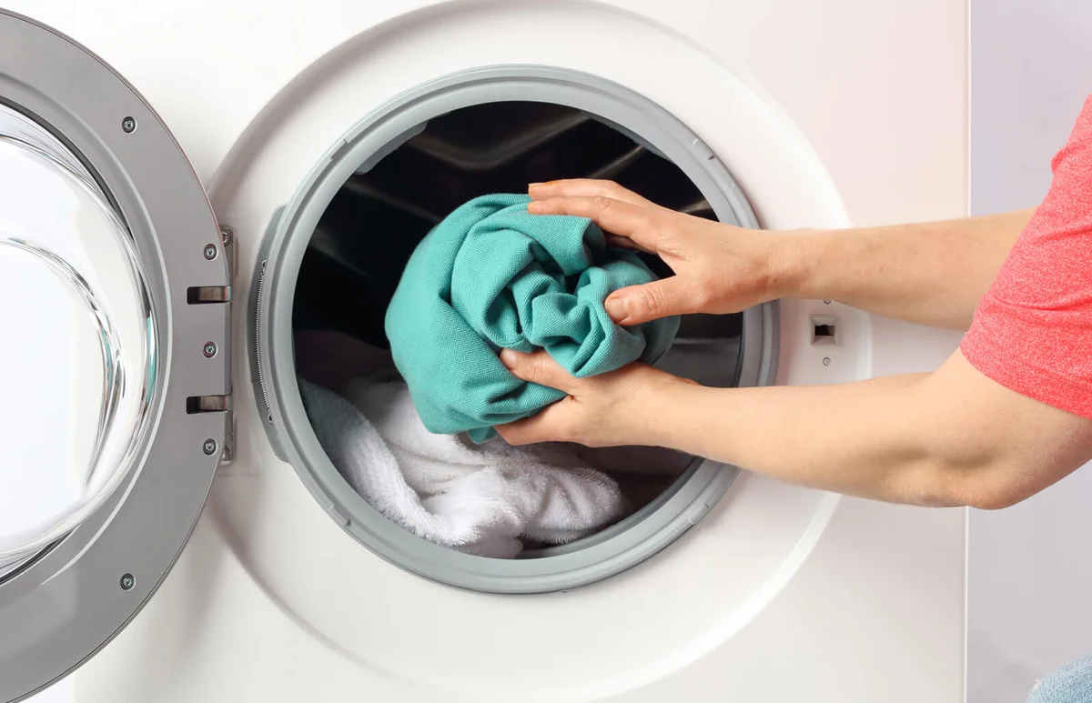 Man Putting Clothes In Washing Machine