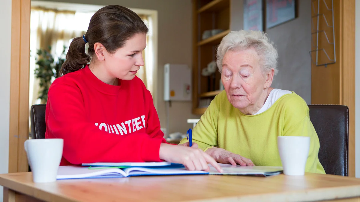 volunteer assisting a senior woman with paperwork