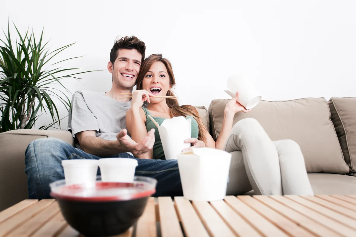 Couple enjoying takeout while watching TV