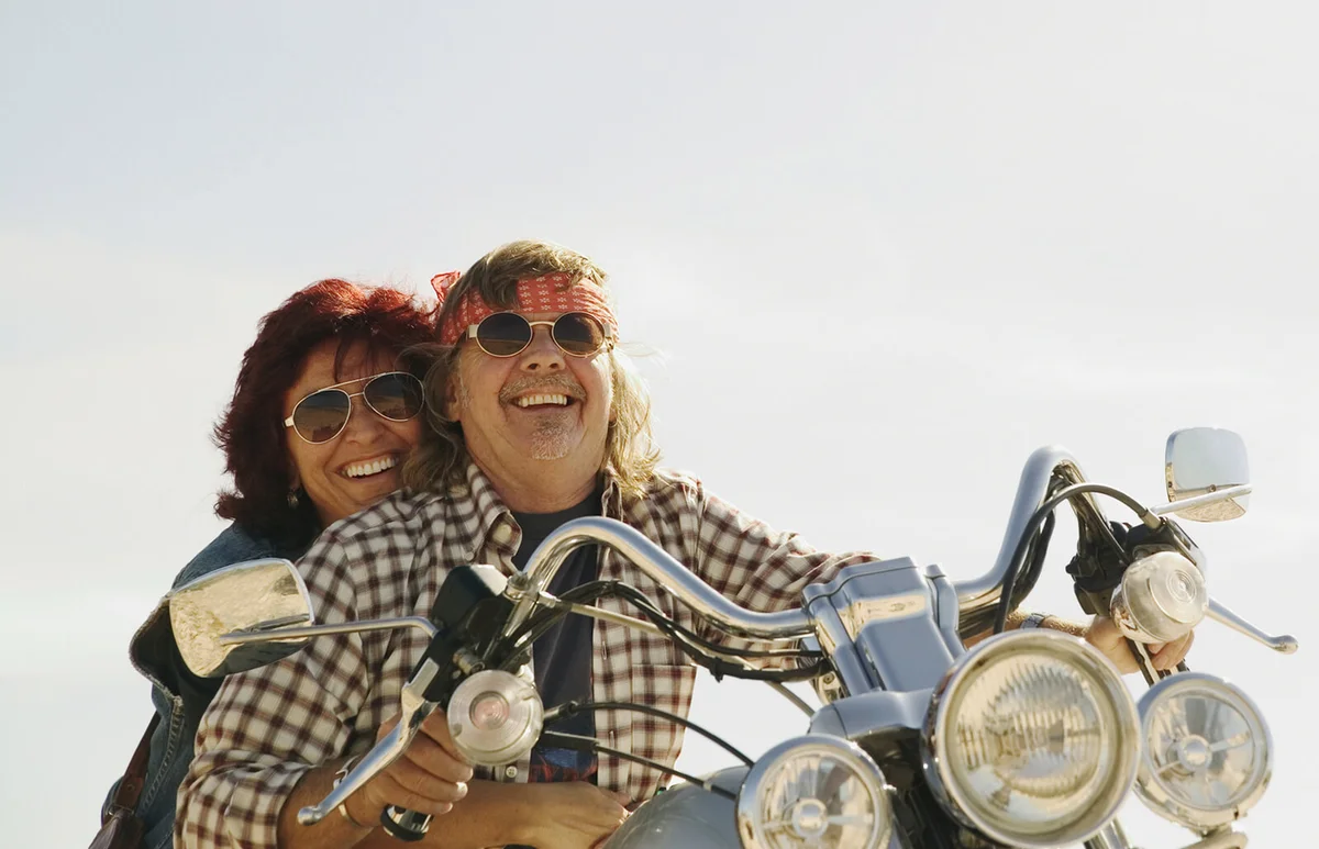 Mature couple on motorbike, wearing sunglasses
