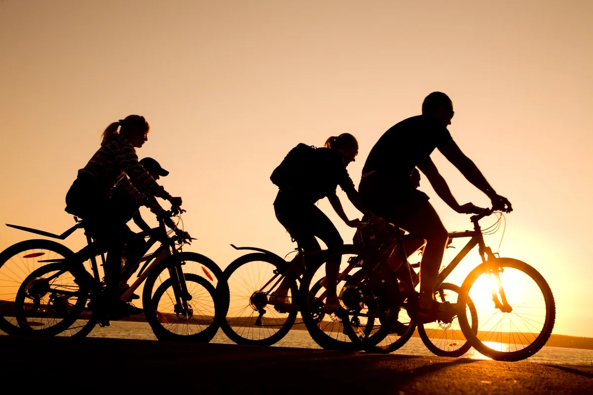 Family riding bicycles at sunset