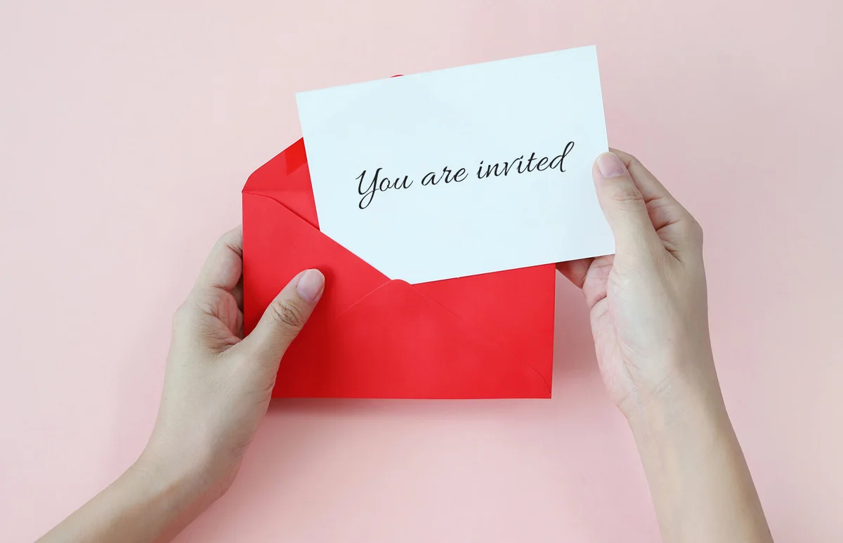 Hand Removing Paper From Envelope Over Pink Background