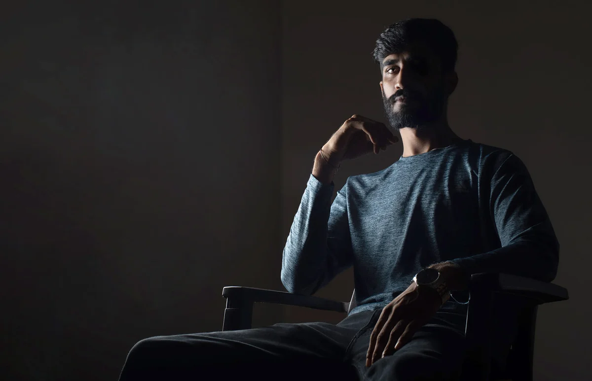 Man Sitting On Chair Against Black Background