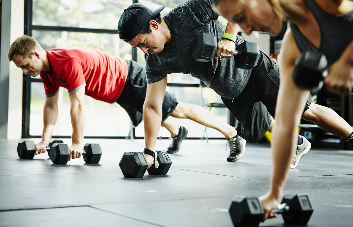 Group of friends doing pushups with dumbbells