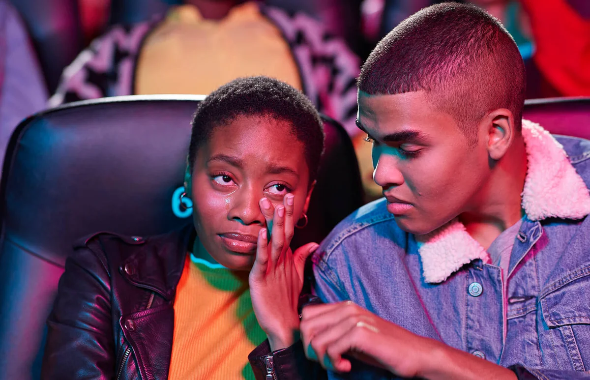 man looking at woman crying while watching movie in theater
