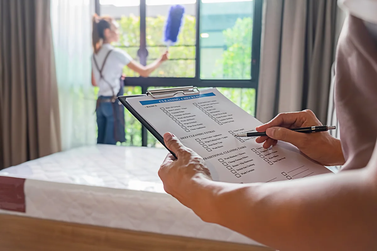 Two women cleaning house using checklist