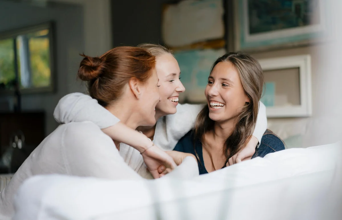 teenage girl hugging mother and sister on couch at home