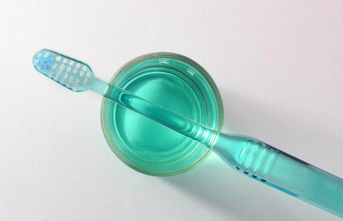 toothbrush over glass with mouthwash top