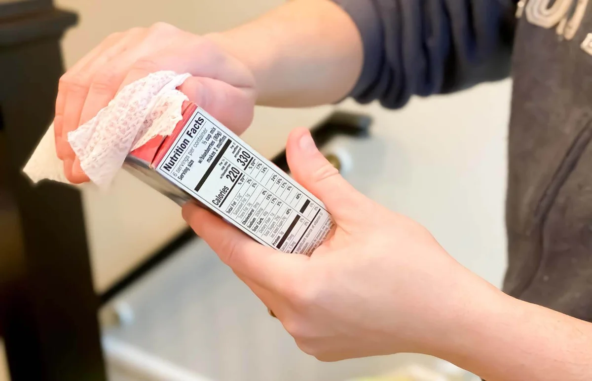 father uses anti-bacterial wipe to sanitize groceries