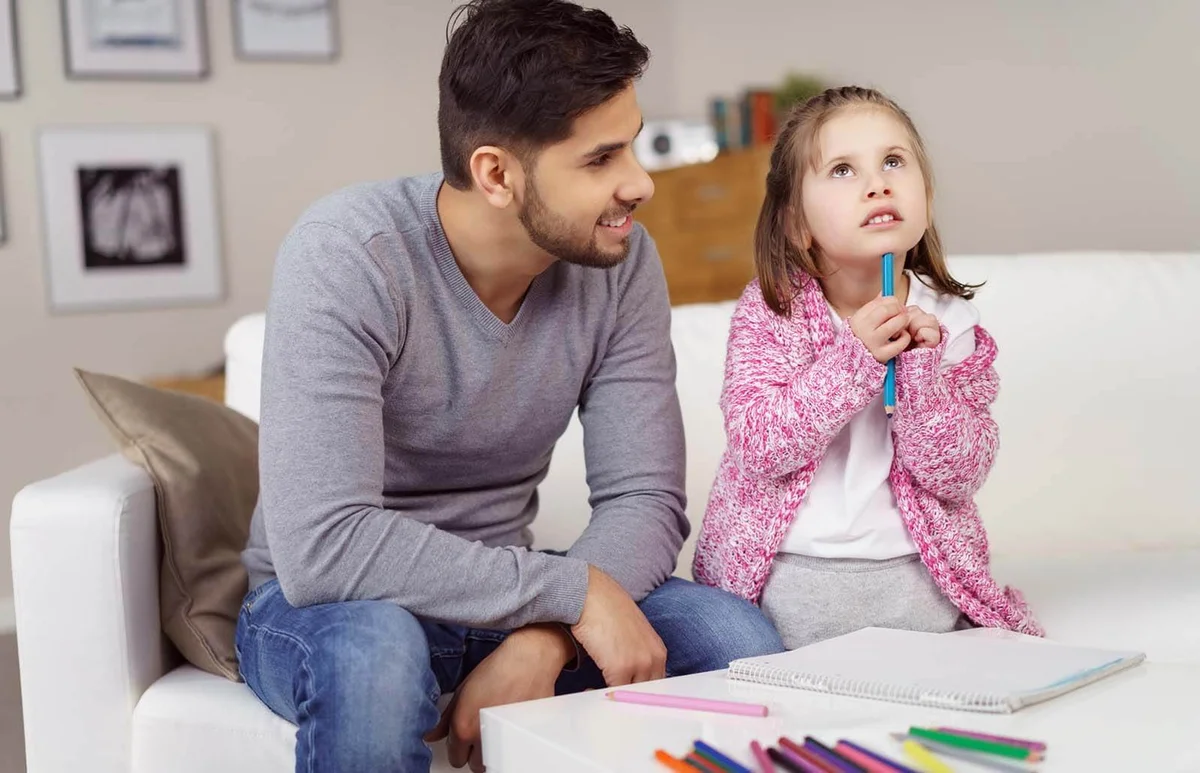 Father sitting with child while coloring