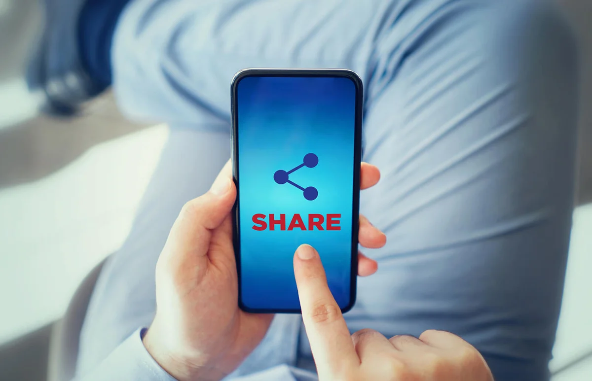 man touching share icon on smart phone
