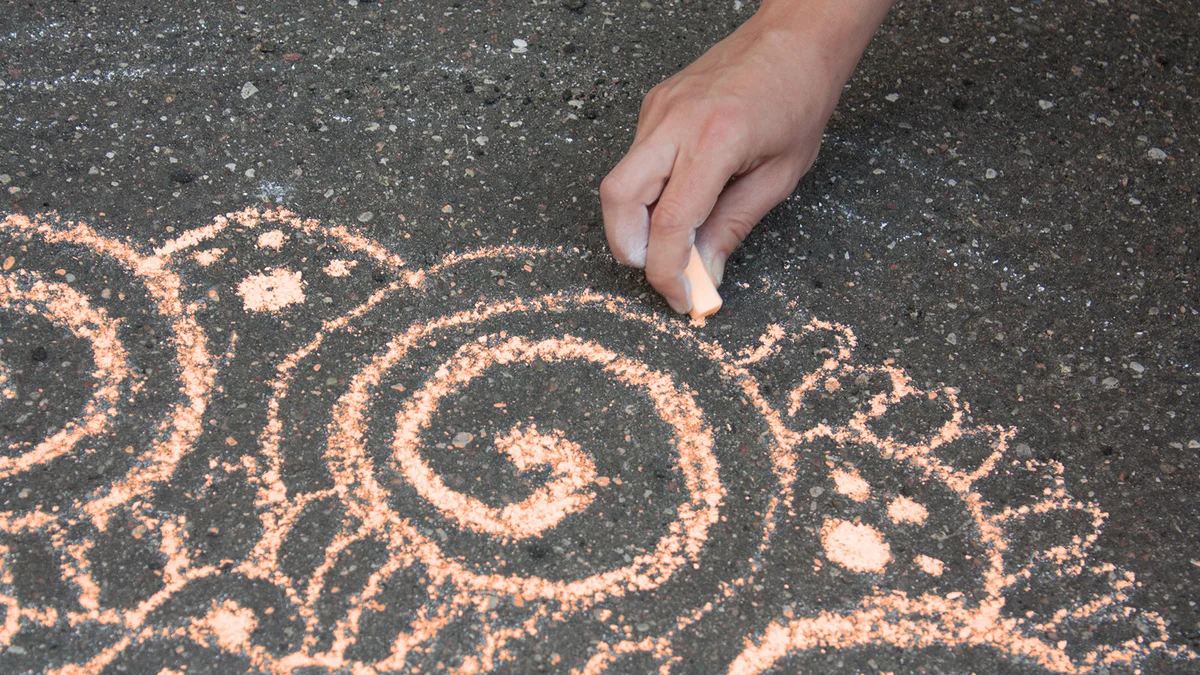 Drawing a Mandala design with sidewalk chalk.