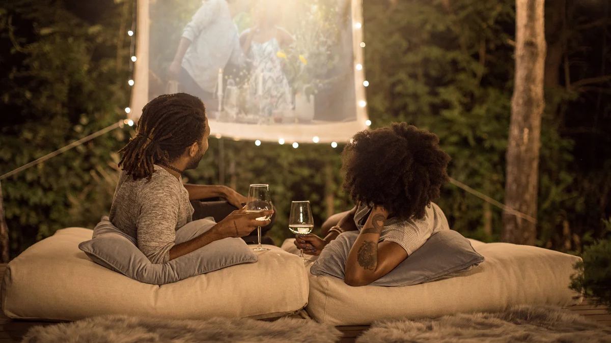 Romantic couple sitting at backyard and watching movie.