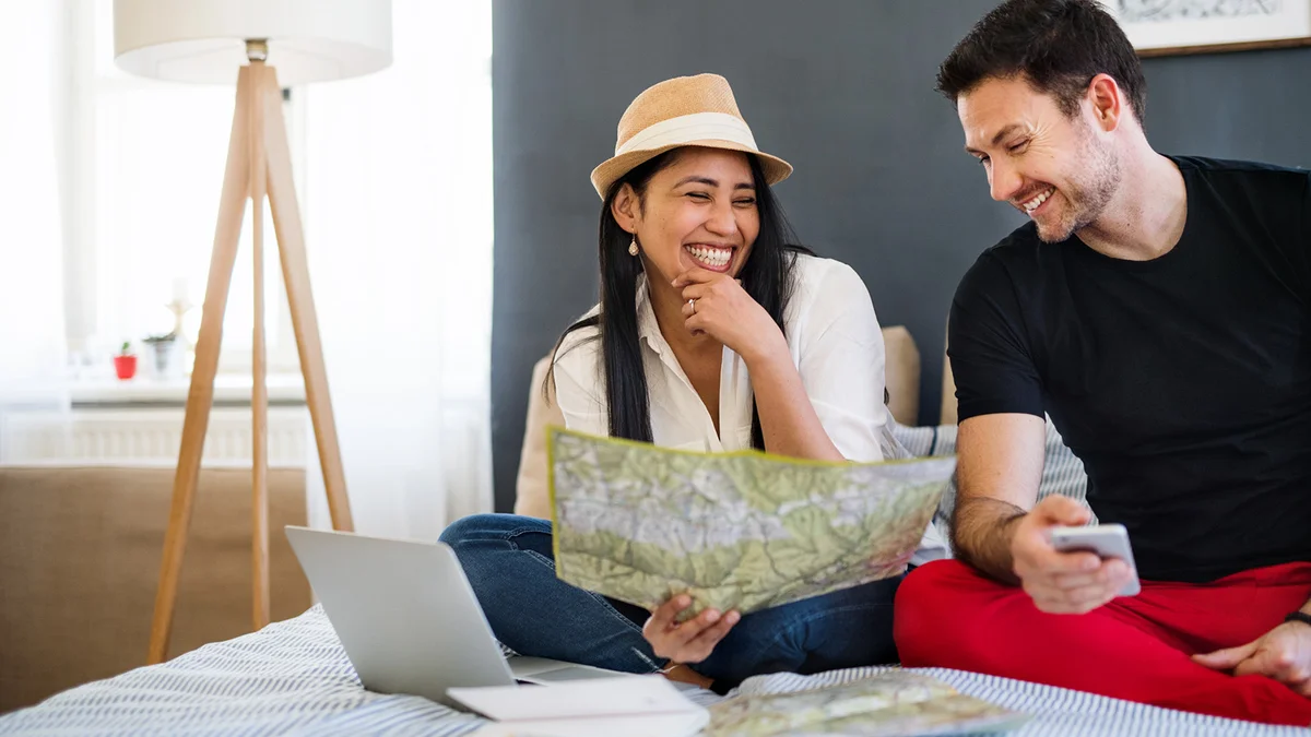 Young couple with laptop and map at home, planning a journey
