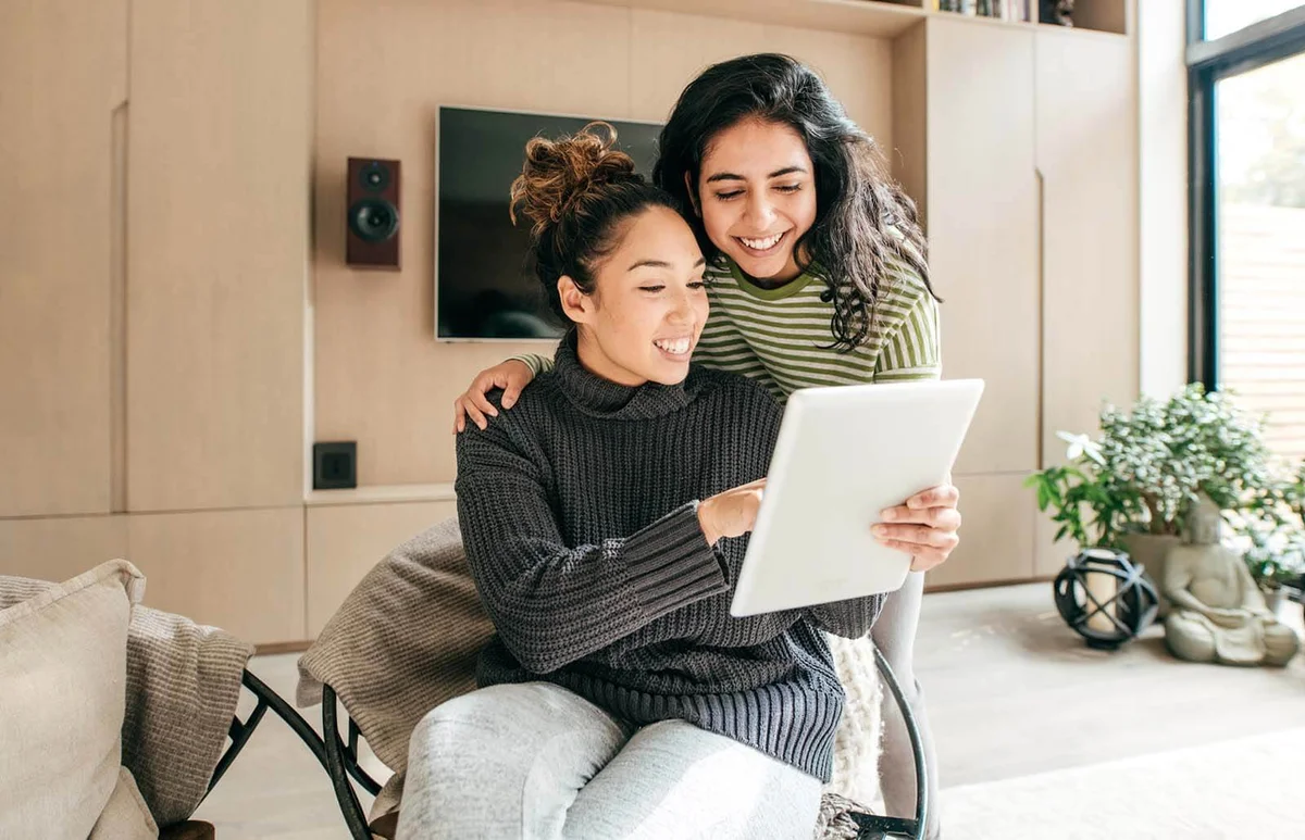 Two teen friends laughing looking at tablet