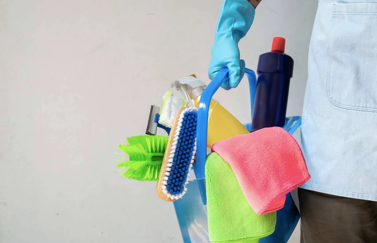 Man holding mop and plastic bucket with brushes