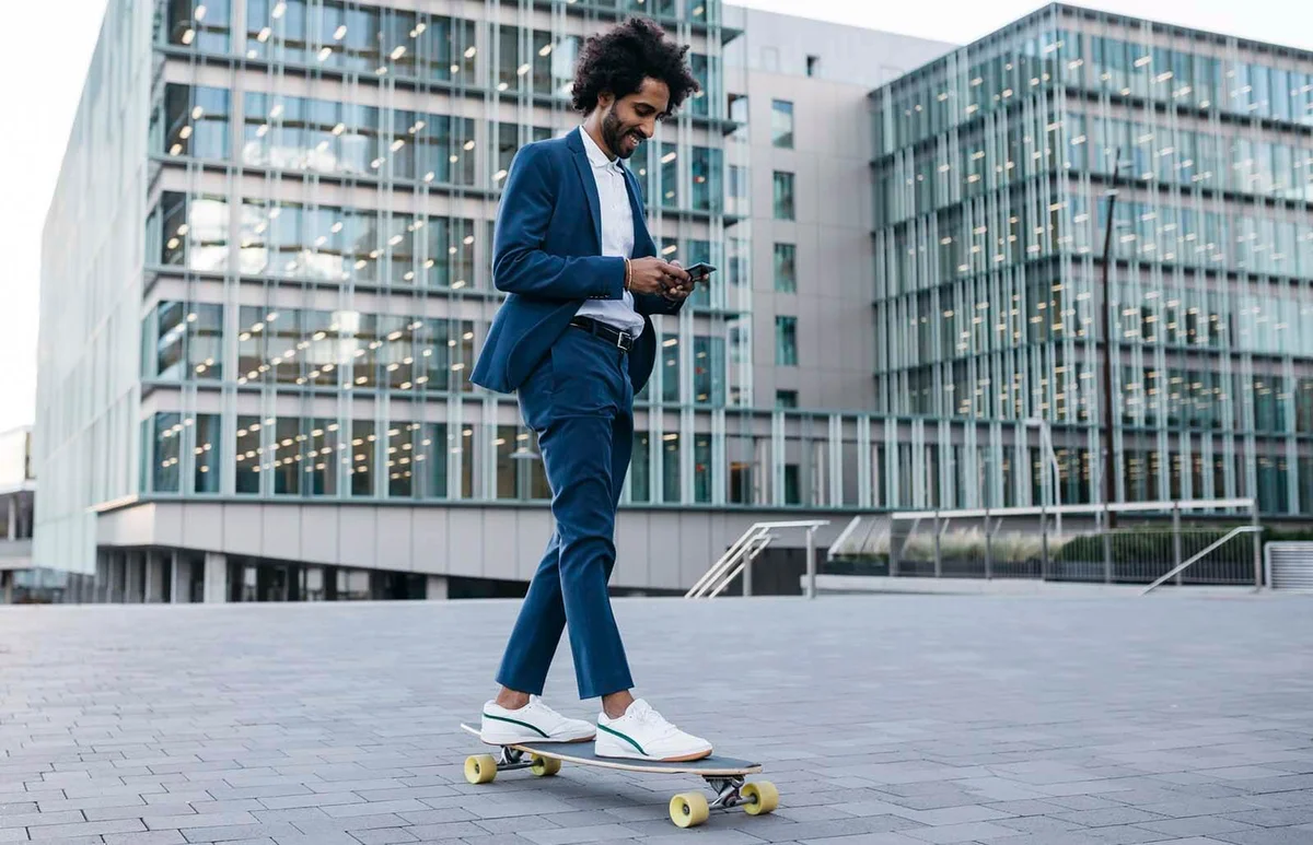 young businessman riding skateboard and using cell phone in the city