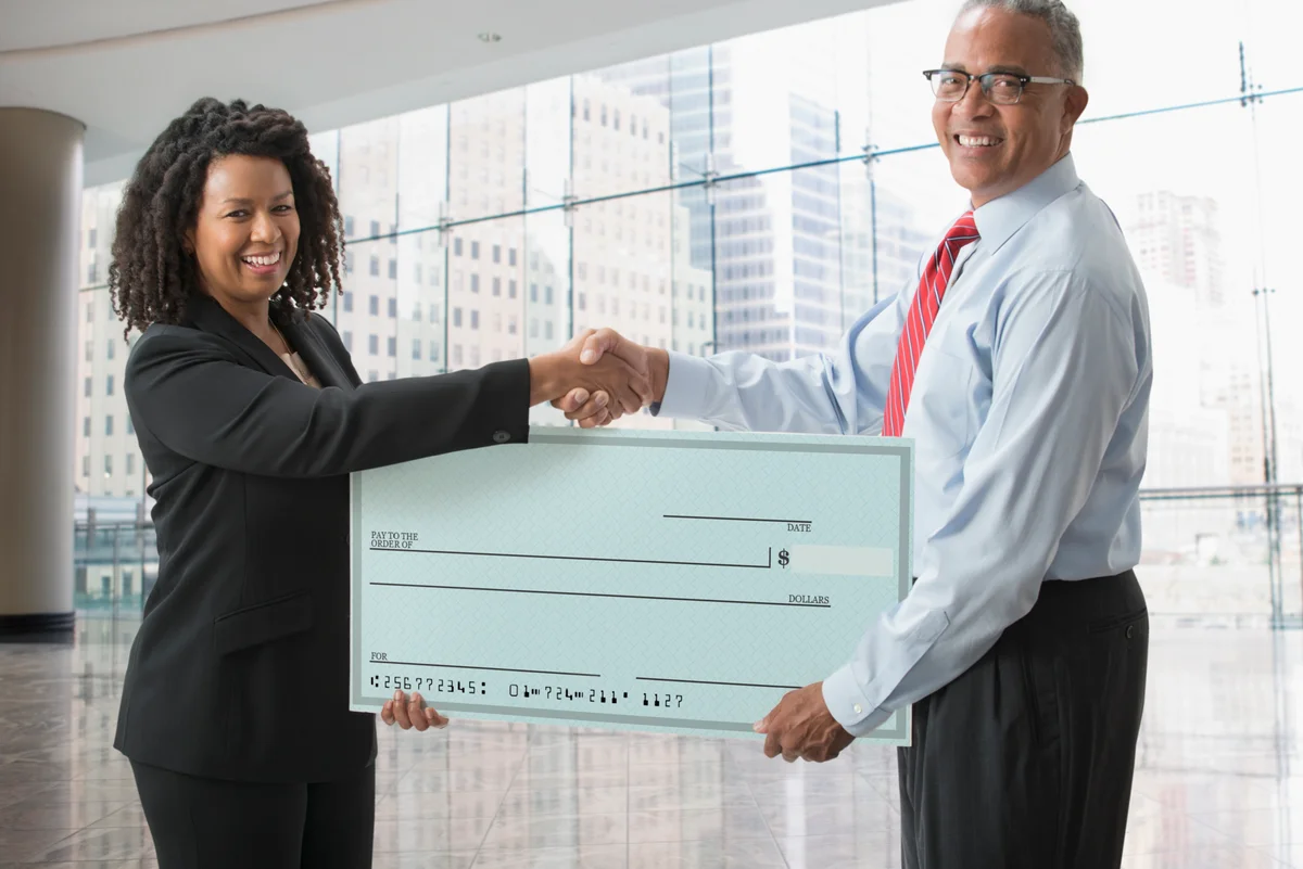 Business woman and man holding blank check