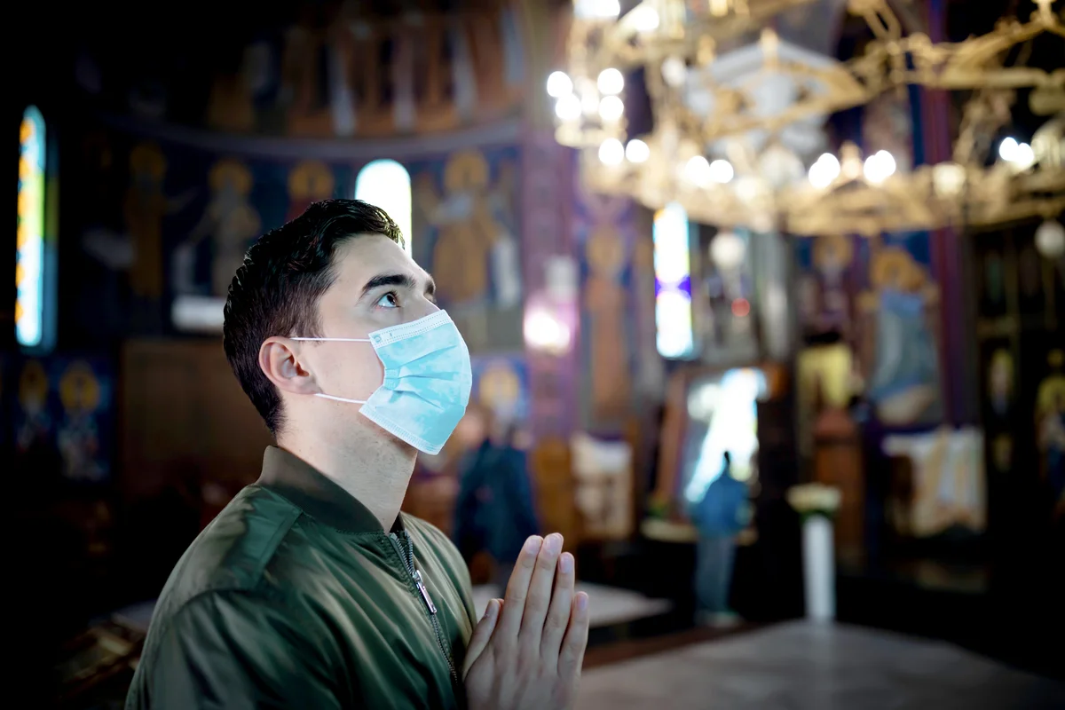 Young man wearing protective mask in church
