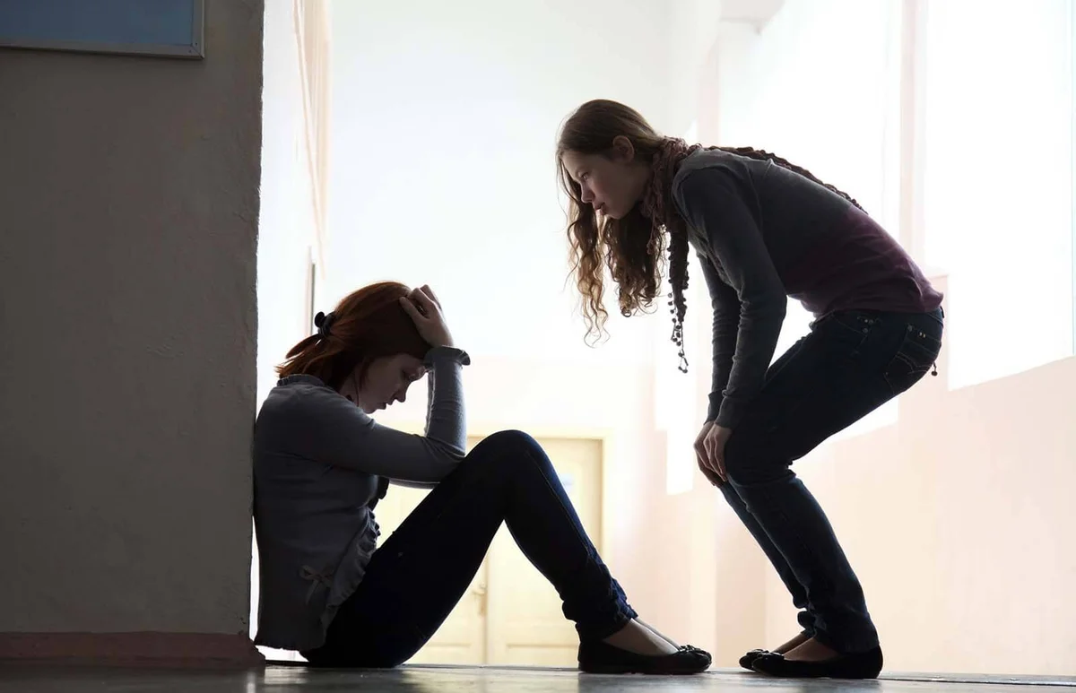 Teen girl offers to help her friend crying on the floor