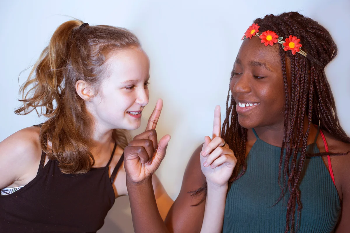 Two teenage girls playing charades