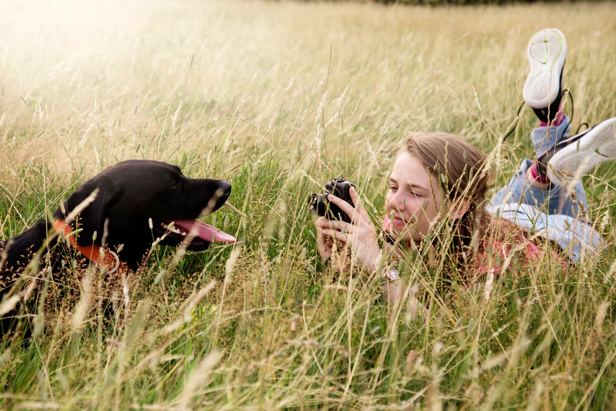 Teenager takes photos of her Labrador retriever dog in park