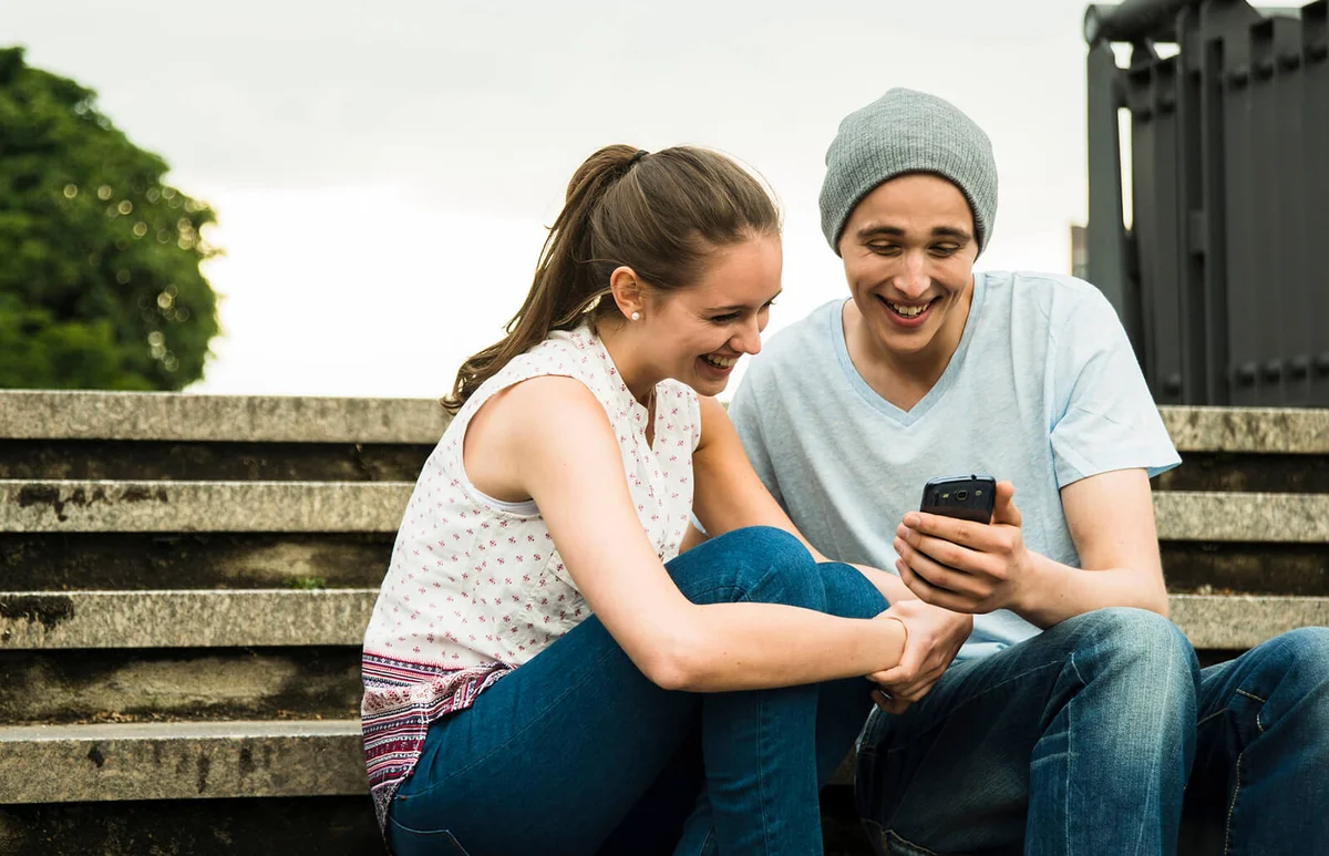 Young couple with smartphone sitting on stairs