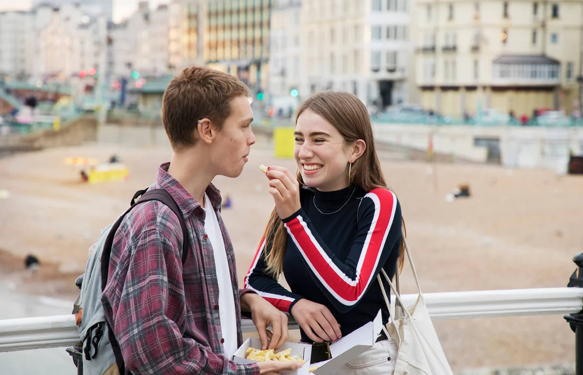 Teenager gives chip to boyfriend standing on promenade