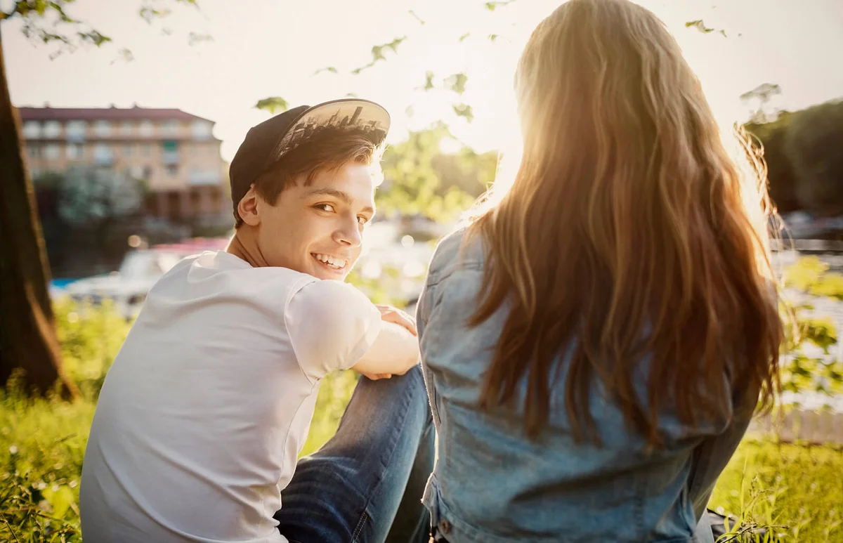 teenager sitting with female friend at lakeshore