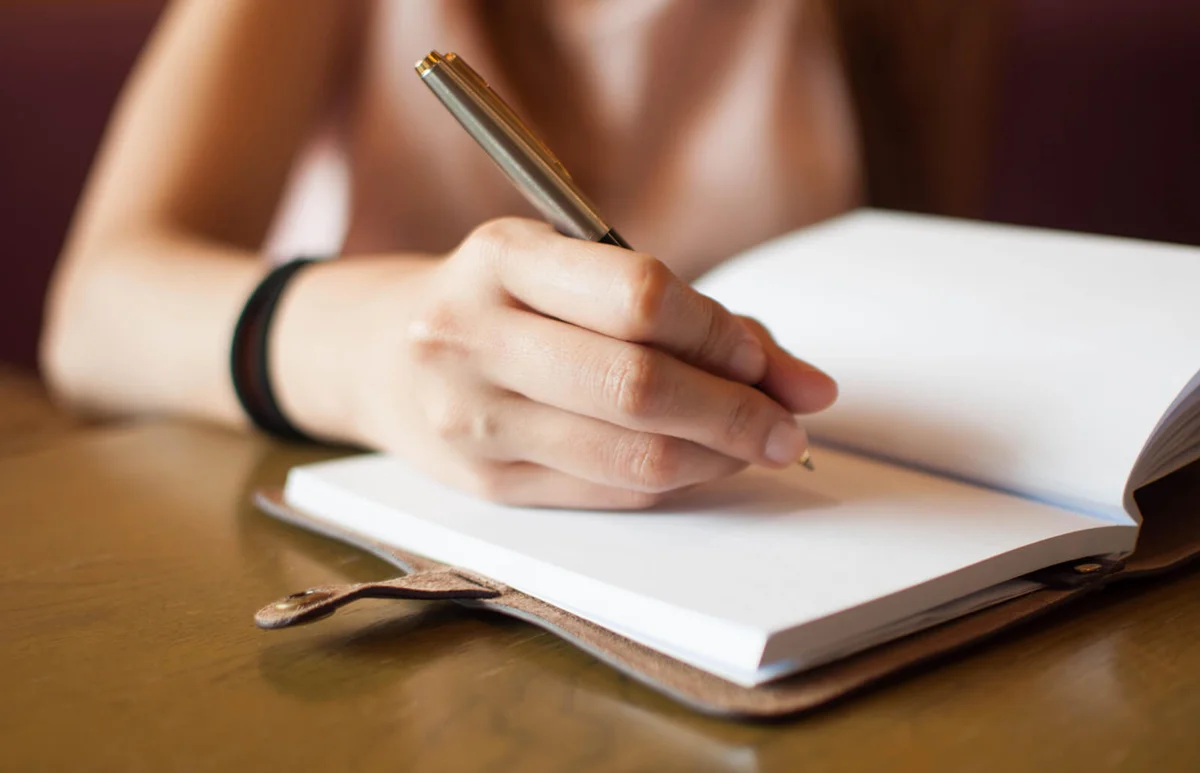 woman is writing on her personal diary