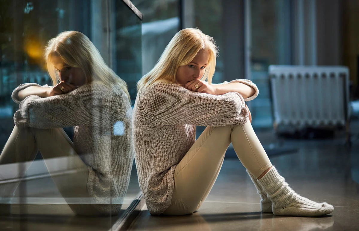 Serious young woman sitting on floor at home