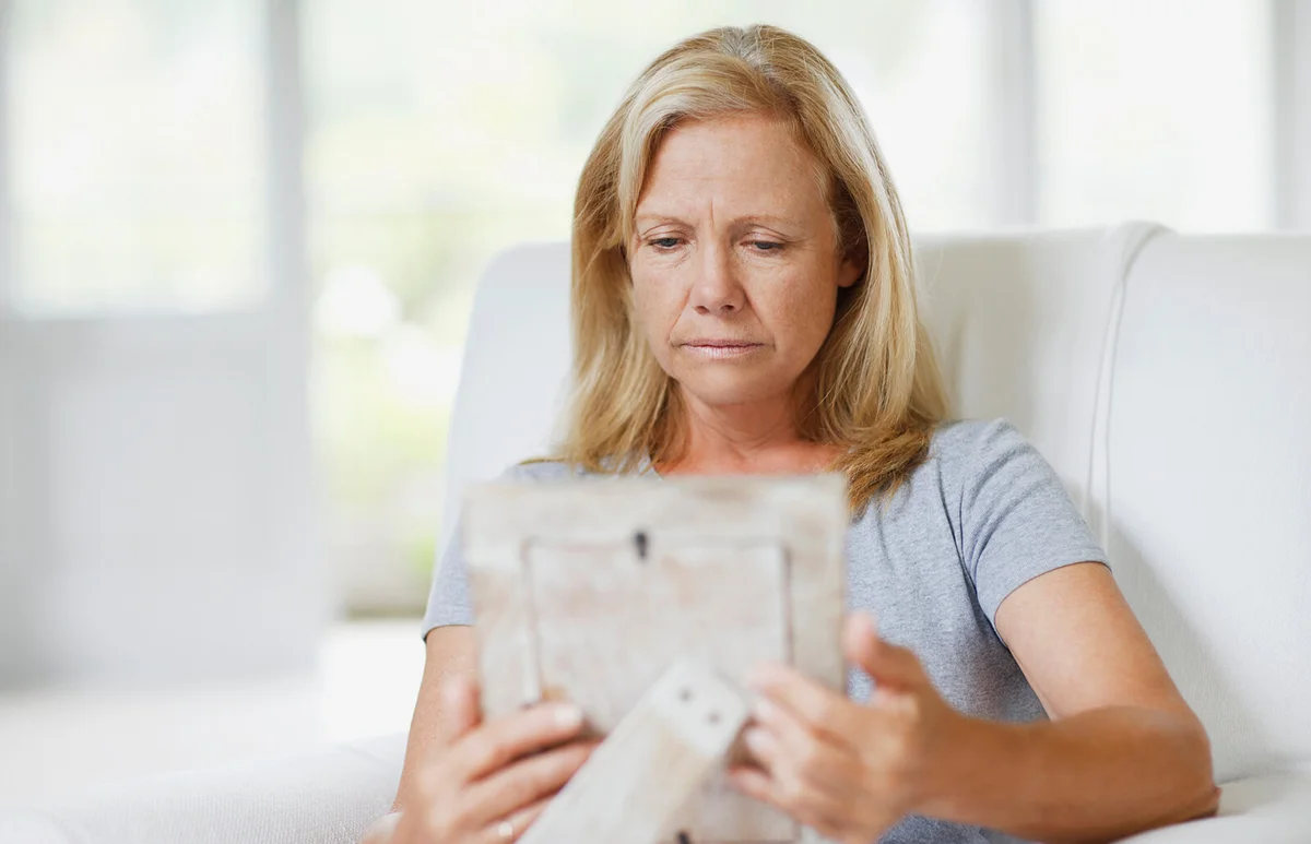 Frowning woman looking at picture frame