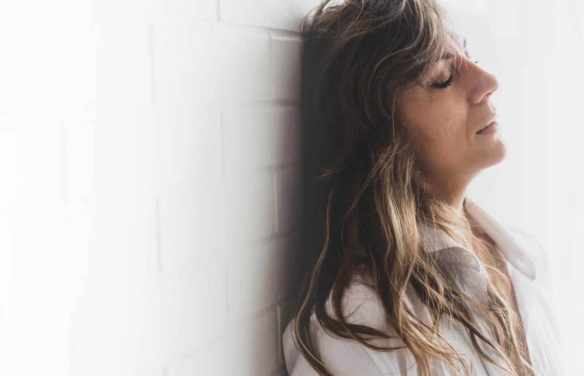 Sad Woman Standing Against White Brick Wall