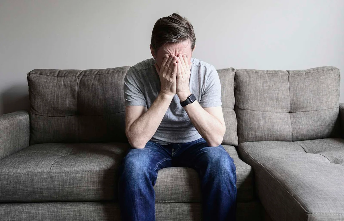Depressed mature man sitting on couch