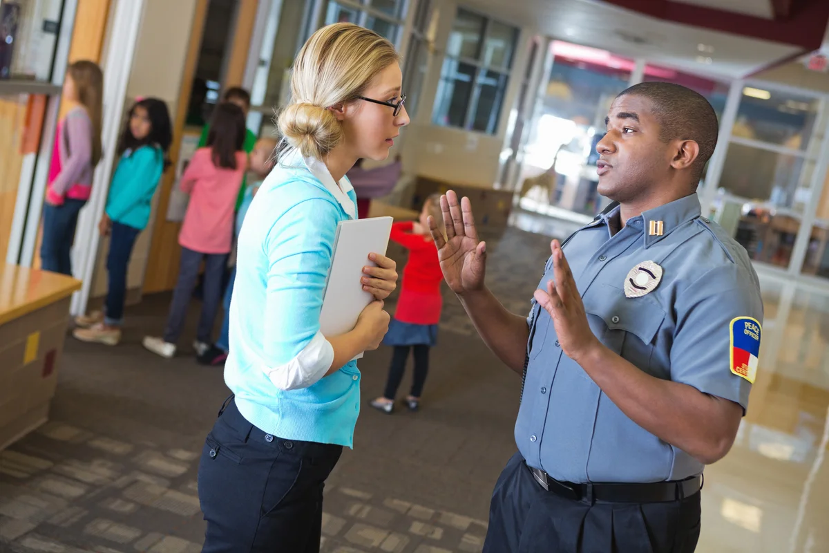Police officer talking to teacher outside her classroom